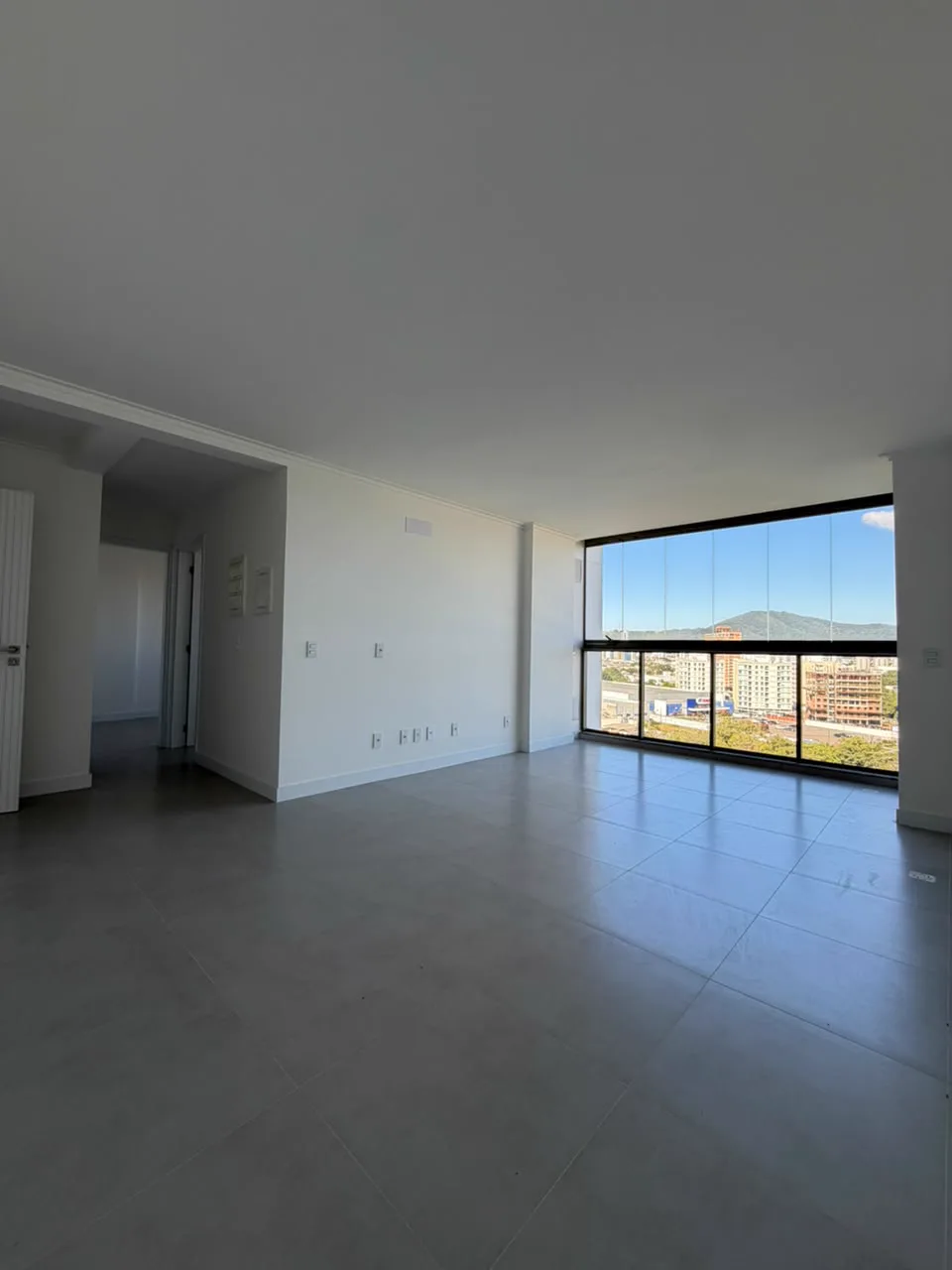 Sala de estar ampla de apartamento em Itajaí com janelão e vista